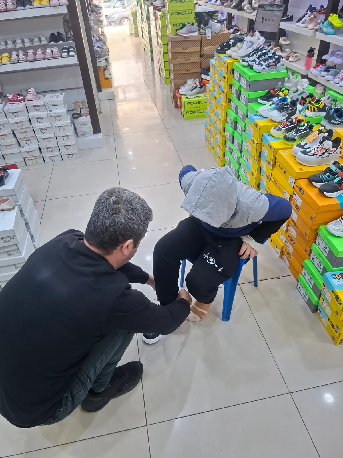Mağazada bir çocuğa ayakkabı giydirilirken